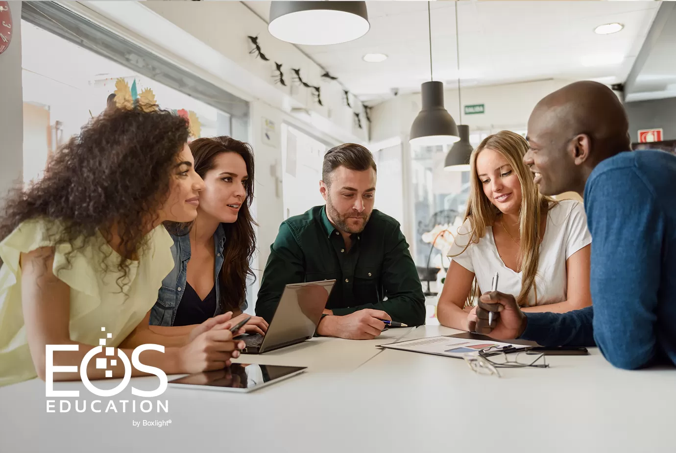 A group arouund a table having a discussion with the EOS logo in the bottom left