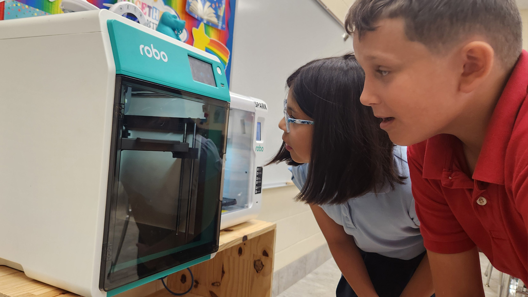 student looking into a 3D printer